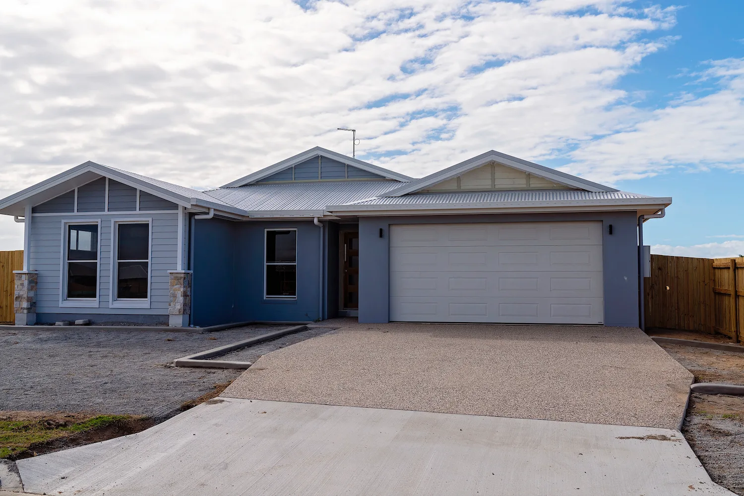 New concrete crossover from the road to a weatherboard home