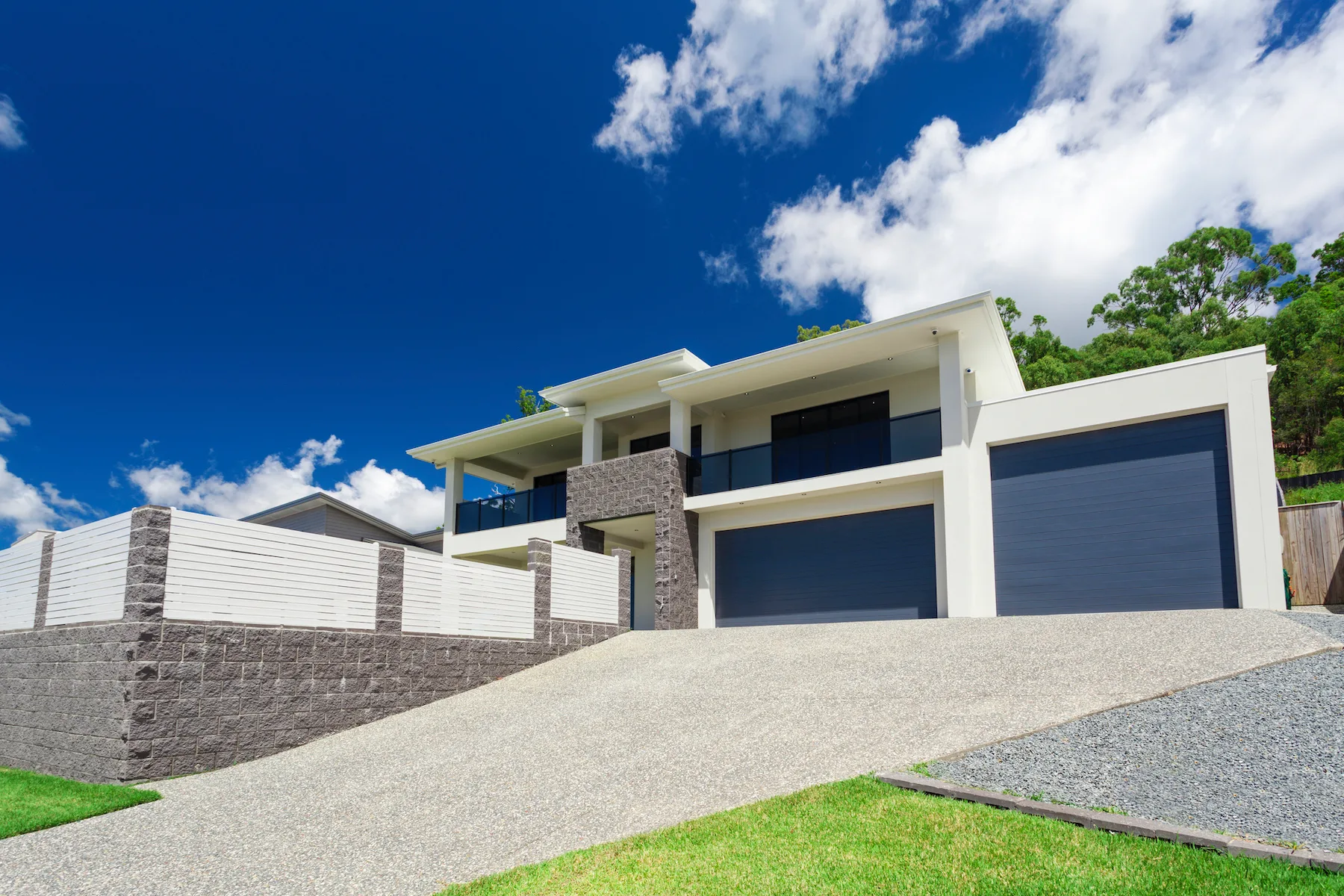 Plain concrete driveway sweeping up to a two-storey home