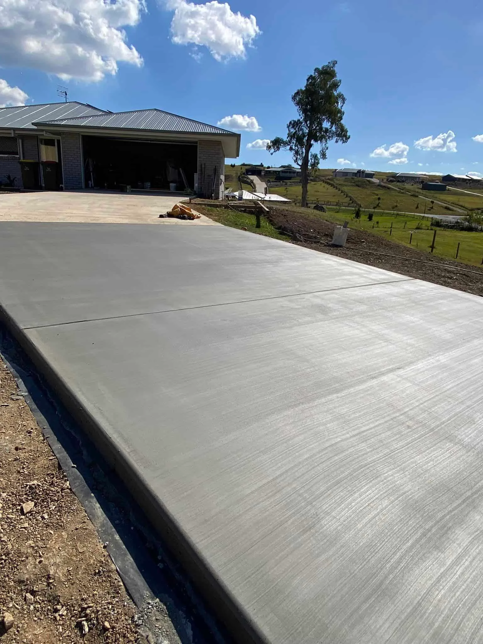 Freshly finished concrete driveway running up a sloping block