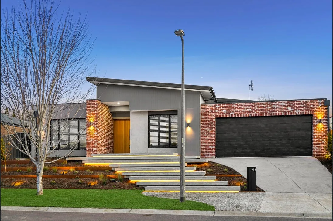 Finished concrete driveway in front of a brick home with landscaped garden steps at dusk
