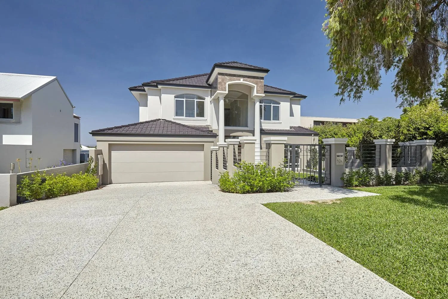 Exposed aggregate driveway in front of a large rendered home