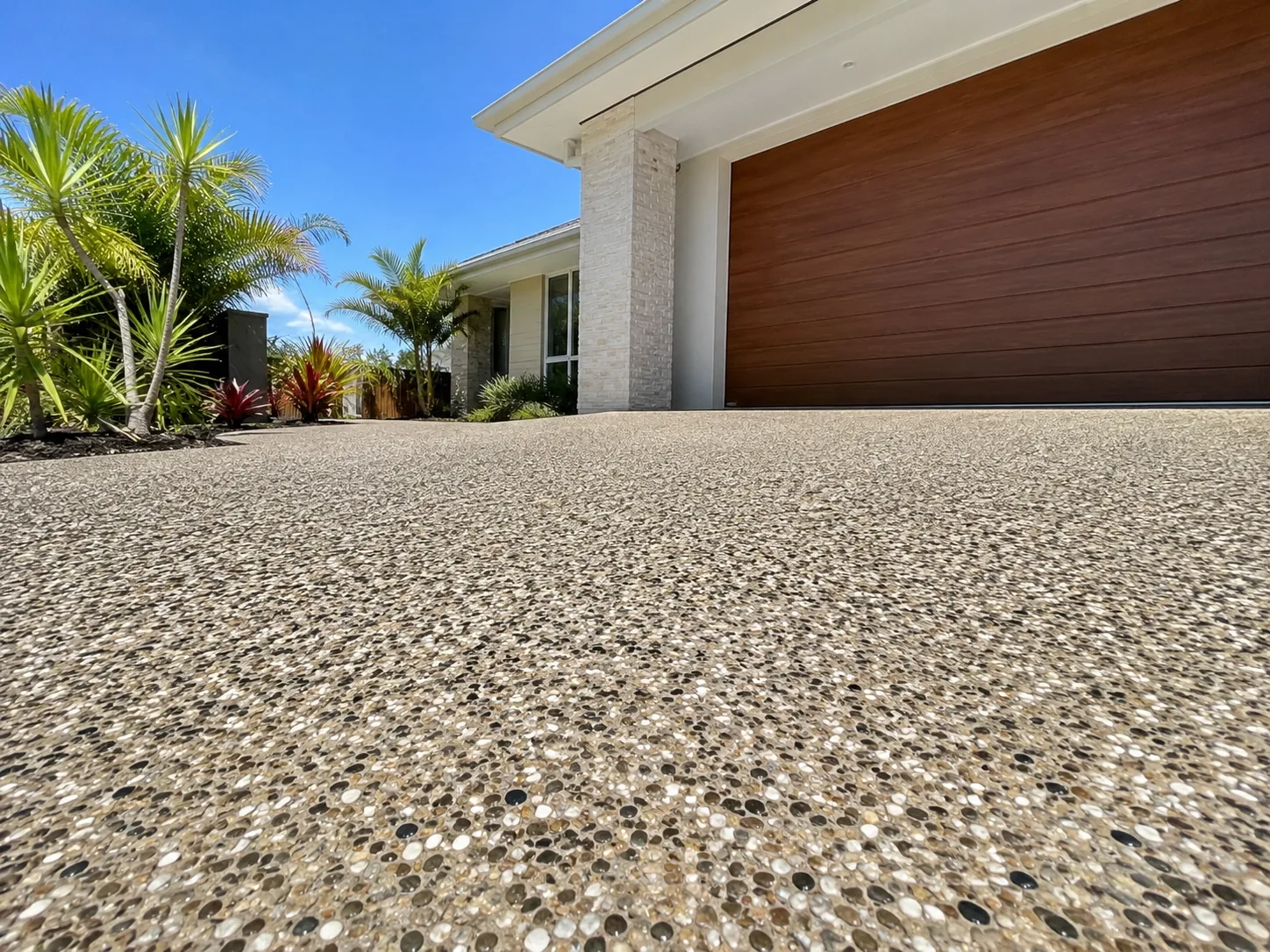 Close-up of an exposed aggregate driveway finish in front of a timber garage door